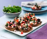 Riesenchampignon-Köpfe mit Tomaten, Oliven und Feta