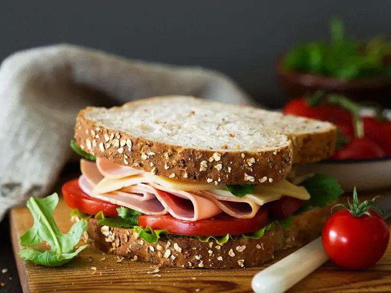 Belegtes Sandwich mit Käse, Schinken, Tomaten und Salat