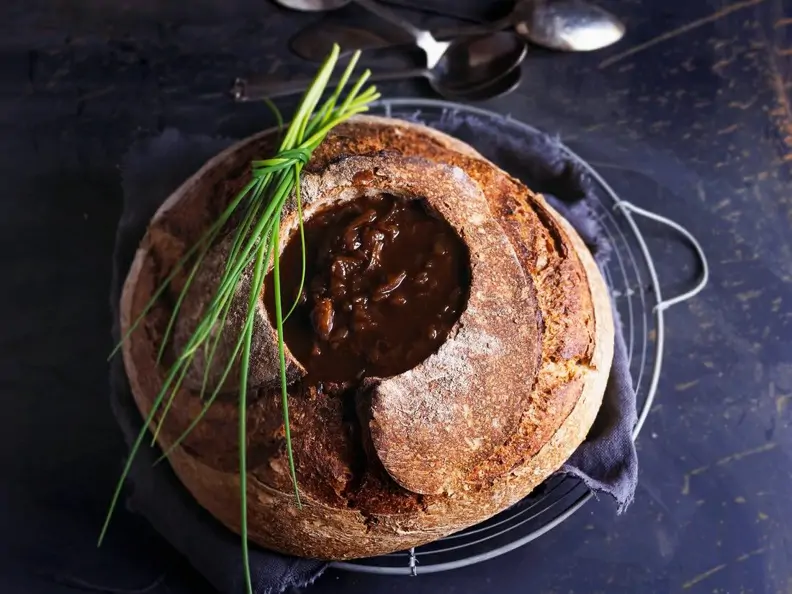 Zwiebelsuppe im Brot serviert