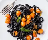 Schwarze Nudeln mit gelben Tomaten