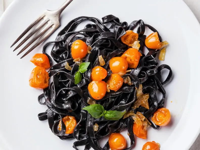 Schwarze Nudeln mit gelben Tomaten
