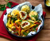 Paella-Reis-Bällchen gefüllt mit Tomaten auf mediterranem Gemüse