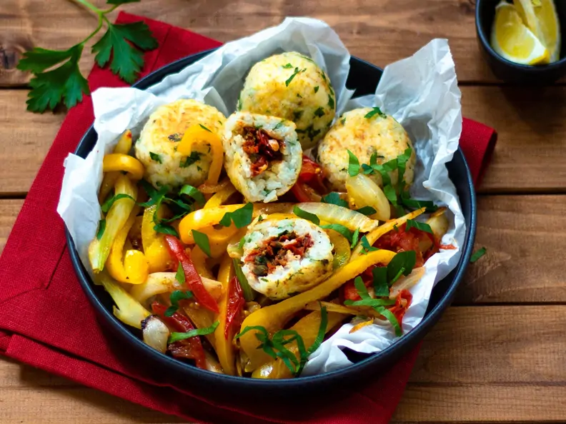 Paella-Reis-Bällchen gefüllt mit Tomaten auf mediterranem Gemüse