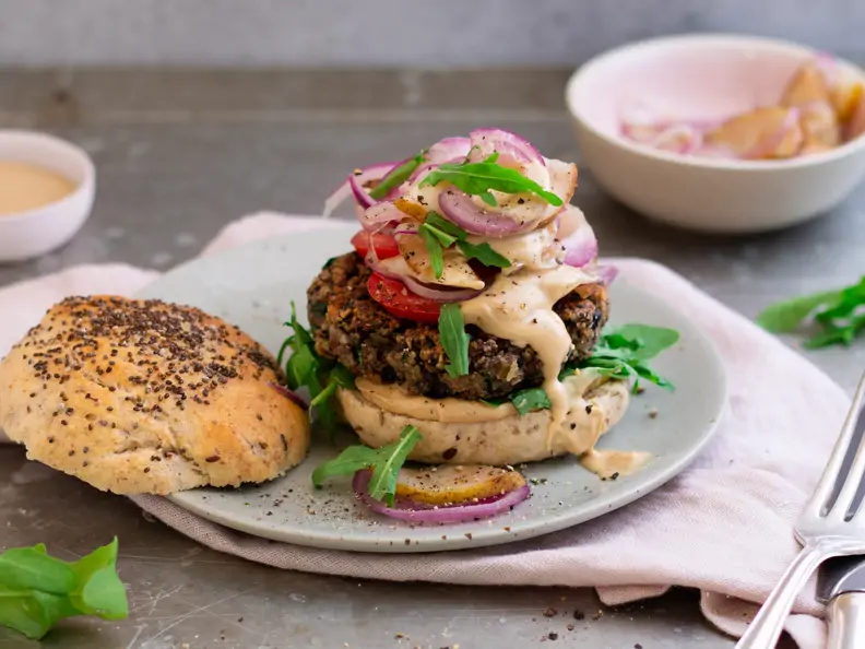 Burger mit Zwiebeln und Birne und nebenliegendem Deckel