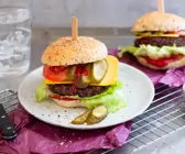 Veganer Cheeseburger mit saftigem Black Bean Patty auf pinkem Papier