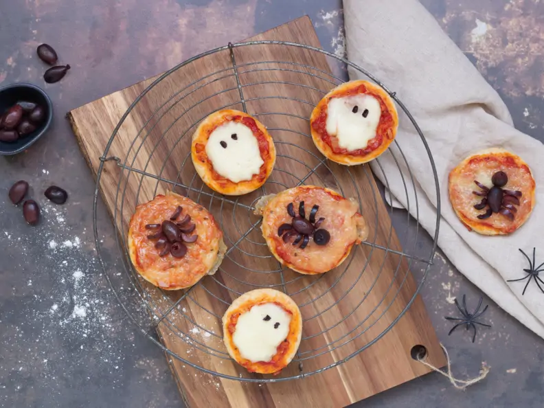 Mini-Pizzen mit Mozzarella und Oliven auf einem Kuchengitter