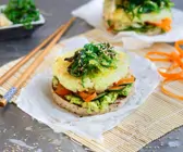 Burger mit Reisbratling und Algensalat auf einer Bambusmatte