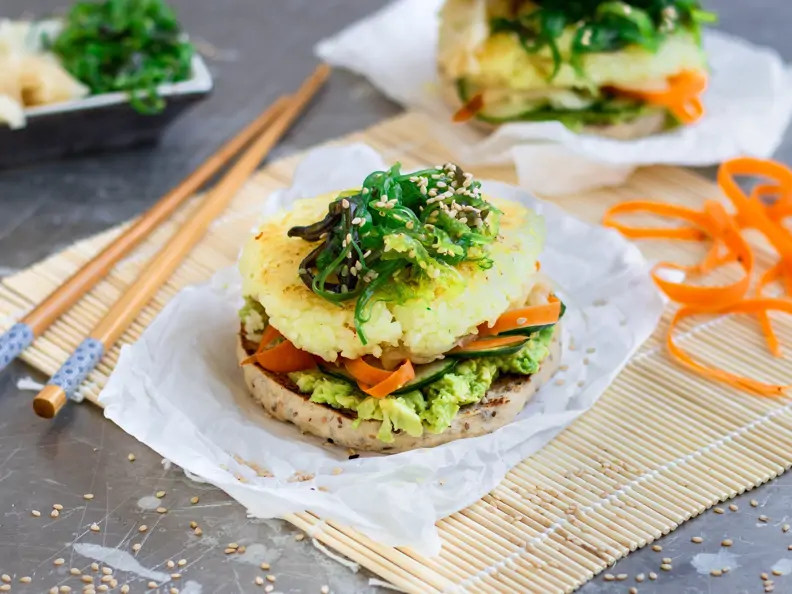 Burger mit Reisbratling und Algensalat auf einer Bambusmatte