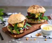 angeschnittener Burger mit einem Haferflockenbratling, Rucola, Haferschmelz und Walnüssen