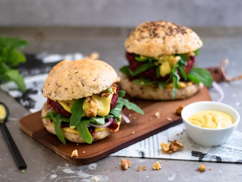 angeschnittener Burger mit einem Haferflockenbratling, Rucola, Haferschmelz und Walnüssen