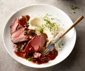 Sauerbraten in Scheiben geschnitten auf Teller mit Sauce