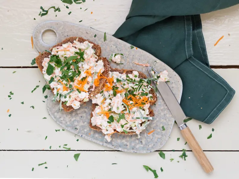 Zwei Brotscheiben mit weißem Frischkäse liegen auf einem Brett