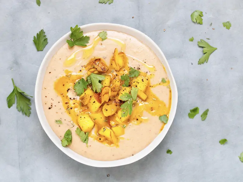 Schale mit Maronensuppe, Birnenwürfel und Nüssen als Topping und gehackter Petersilie