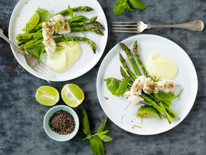 Fischspieße auf grünem Spargel mit Limettensauce