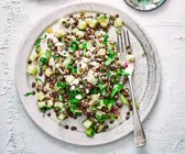Warmer Linsensalat mit Schafskäse auf grauem Teller 