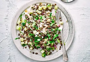 Warmer Linsensalat mit Schafskäse auf grauem Teller 