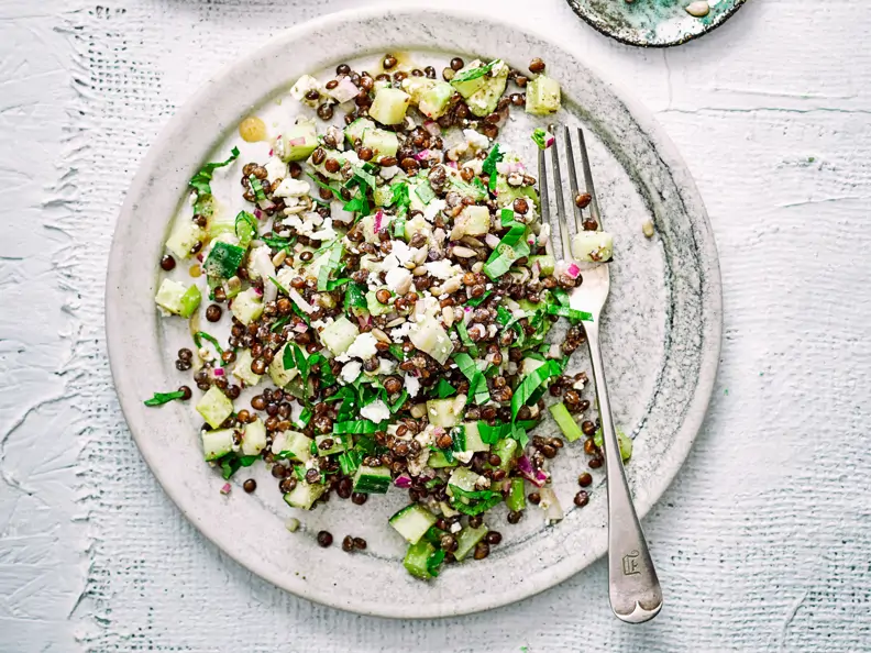 Warmer Linsensalat mit Schafskäse auf grauem Teller 
