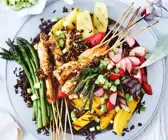Garnelenspieße mit Spargel, Obst und schwarzem Reis