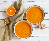 Süßkartoffelsuppe mit Orange und Kurkuma vor weißem Hintergrund