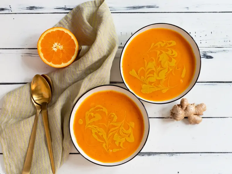 Süßkartoffelsuppe mit Orange und Kurkuma vor weißem Hintergrund