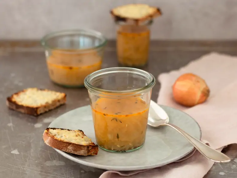 Zwiebelsuppe im Glas auf hellem Teller