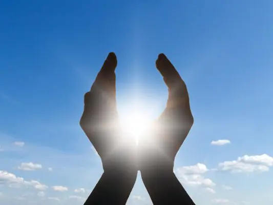 Hände im Gegenlicht vor blauem Himmel 