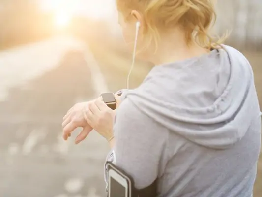 Frau schaut beim Joggen auf ihre Pulsuhr
