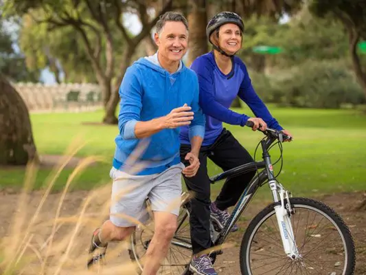 Älteres Paar joggt und fährt Rad im Park 