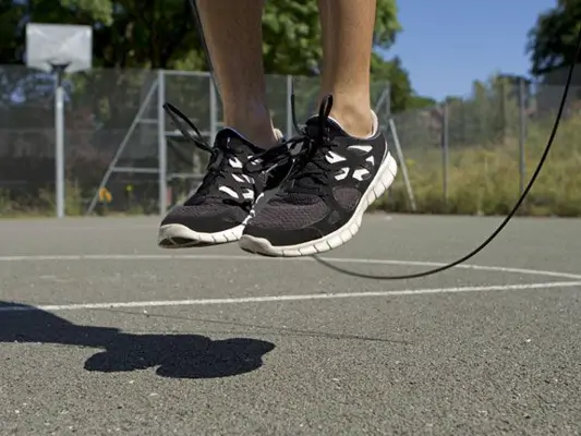 Bewegung pusht Stoffwechsel: Ein Springseil und Füße in der Luft auf einem Basketballplatz