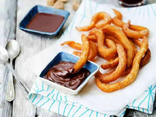 Selbstgemachte Churros mit Schokoladensauce auf einem Teller 
