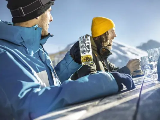 Zwei Skifahrer trinken auf der Alm Weizenbier 