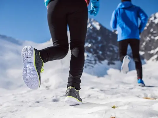 Zwei Menschen joggen im Schnee 