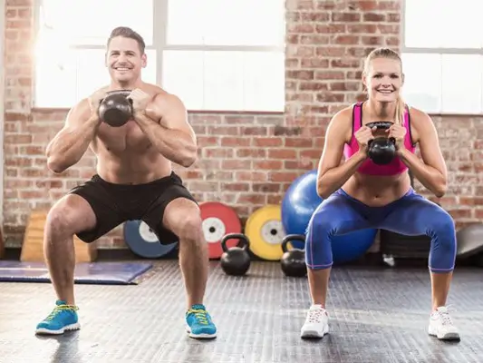 Muskulöses Paar trainiert mit Kettlebells
