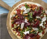Kartoffelpizza mit Pfifferlingen auf einem runden Holzbrett