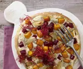 Pizza mit roter Bete auf einem Holzbrett und einer Gabel