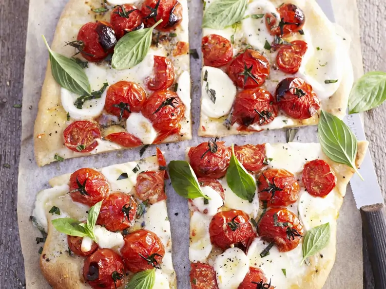 Pizza mit Tomaten, Mozzarella und Basilikum