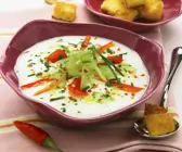 Helle Suppe in violetter Schale mit Gemüse-Topping und Toast