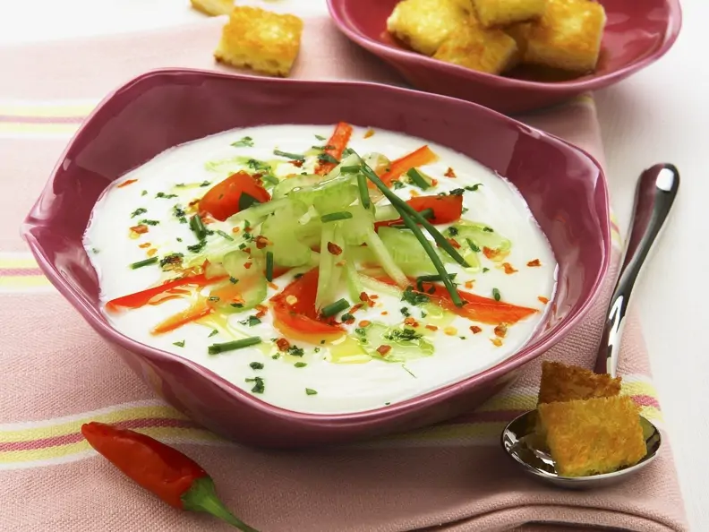 Helle Suppe in violetter Schale mit Gemüse-Topping und Toast
