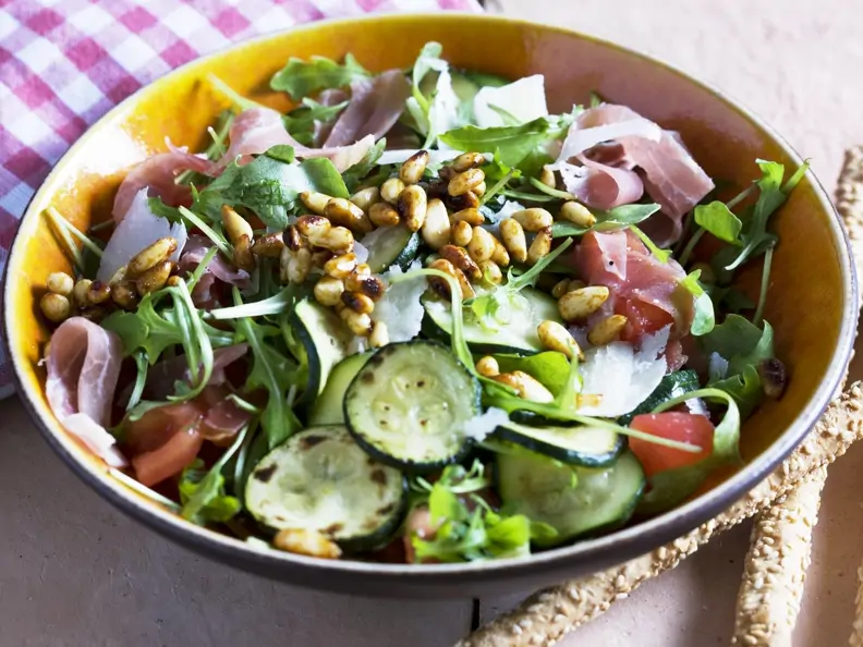 Gemischter grüner Salat mit Zucchini, Pinienkernen und Rohschinken