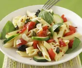 Pastasalat mit Oliven, Tomaten und Basilikumblättern