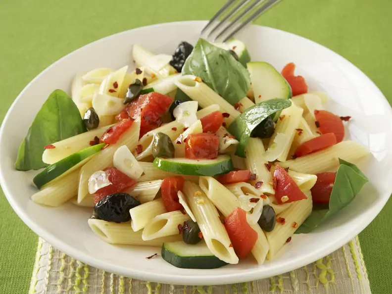 Pastasalat mit Oliven, Tomaten und Basilikumblättern