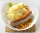 Bratwurst mit Kartoffel-Zwiebel-Brei auf einem weißen Teller
