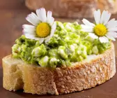 Brot mit grünem Hüttenkäse und Gänseblümchen