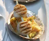 Spießchen mit Jakobsmuscheln auf tropischem Obstsalat