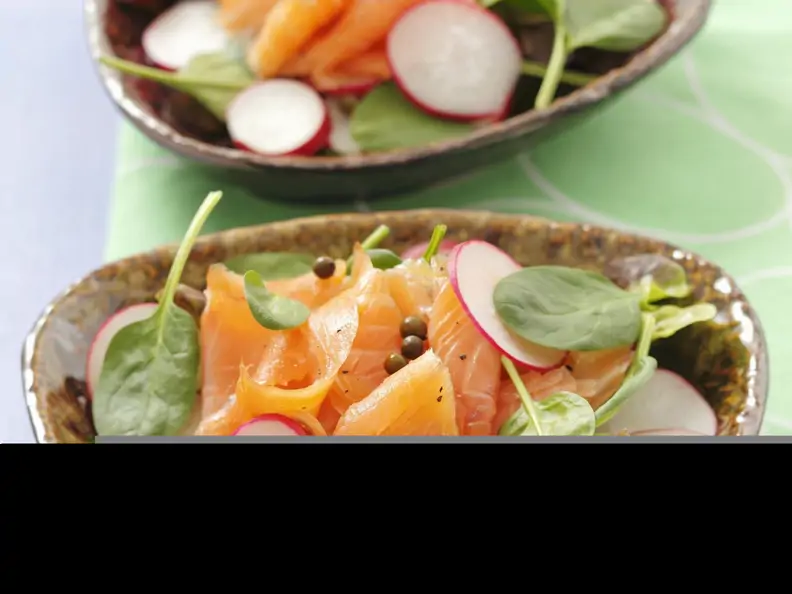 Salat mit Spinat, geräuchertem Lachs, Radieschen und Pfefferkörnern