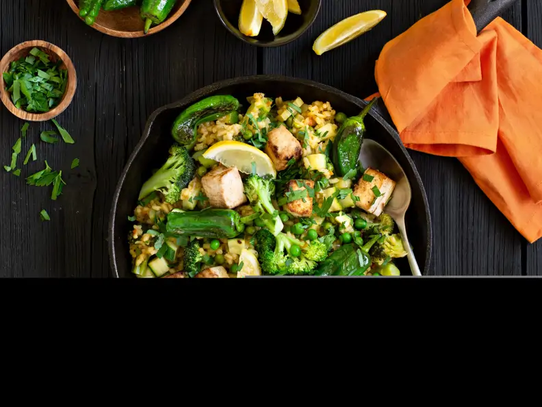 Grüne Paella mit Tofu, Bratpaprika, Erbsen und Zucchini
