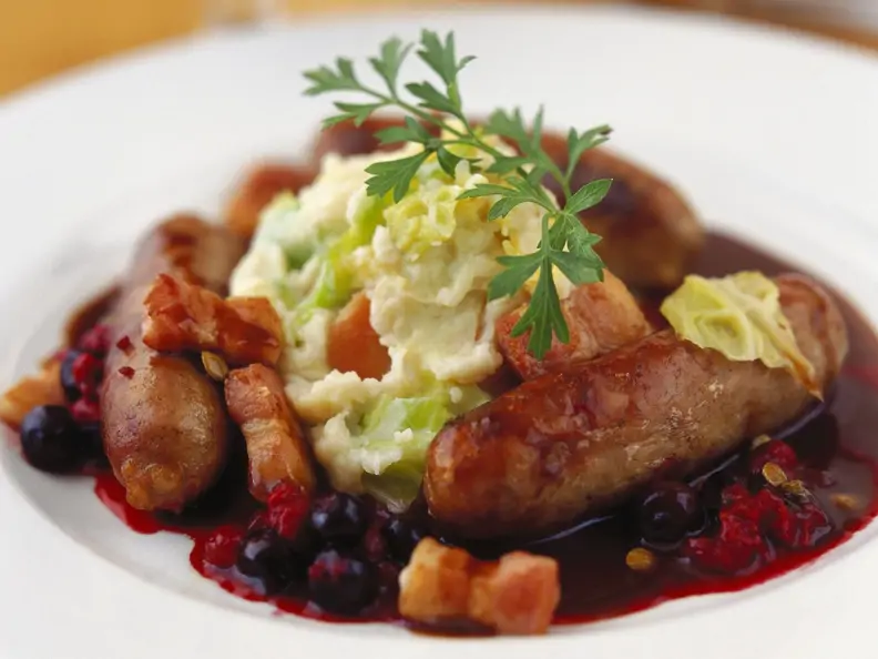 Bratwurst mit Kartoffelbrei, Speck und Blaubeersoße