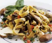 Tagliatelle mit Steinpilzen mit Basilikum garniert auf weißem Teller