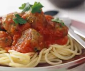 Fleischbällchen in Tomatensauce auf Spaghetti, serviert auf rotem Teller