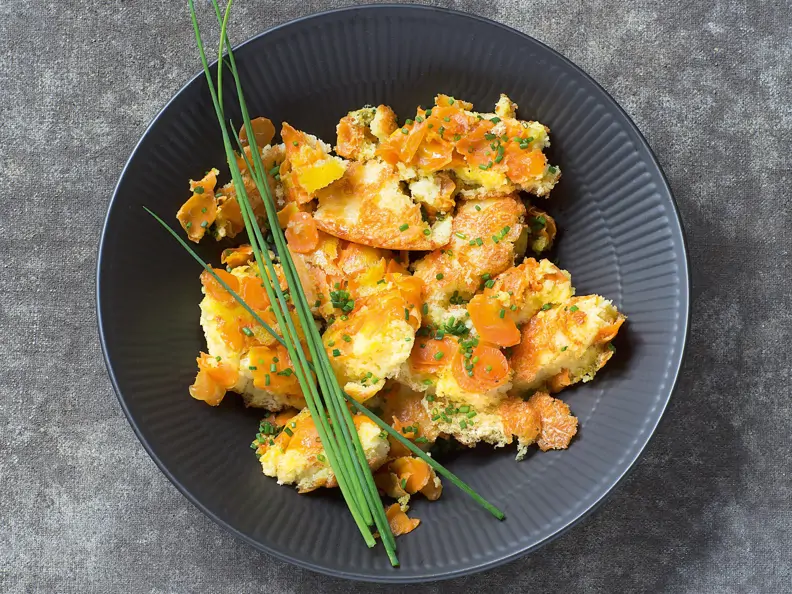 Möhren-Kardamom-Schmarrn mit Gruyère in dunklem tiefem Teller